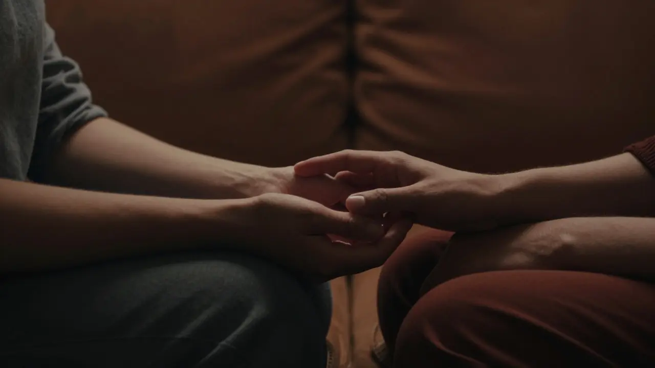 Detail dvou lidí v tichém, intimním kontaktu symbolizující důvěru a přítomnost.